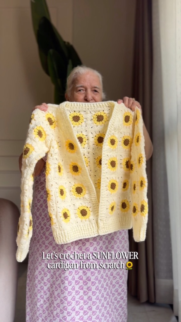 Caught Craft Handed’s Dadi holding a cream crochet cardigan decorated with sunflower motifs
